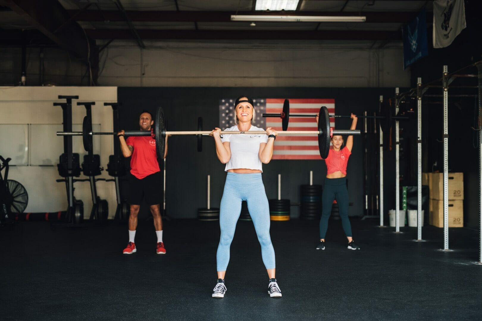 People lifting barbells over head on training at LFT GYM